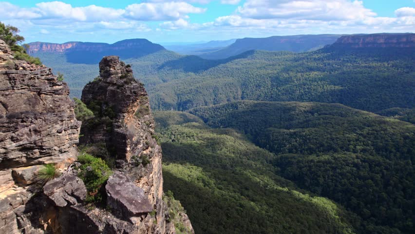 A breathtaking aerial view of Blue Mountains National Park showcases dramatic cliffs and valleys blanketed in eucalyptus forests. Australia's iconic wilderness in golden sunlight.