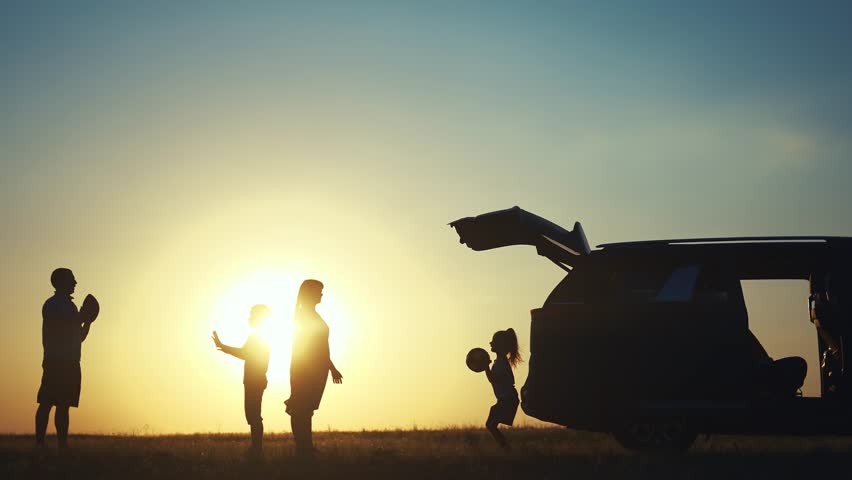 family traveling by car. family watching sunset silhouette next to the car in the park. family playing ball. people in the park. family lifestyle car camping resting in nature