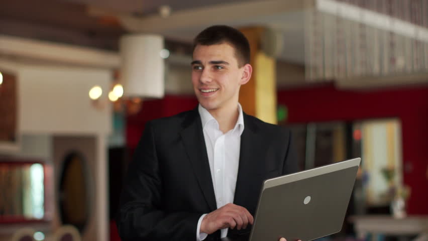 Businessman standing in cafe and typing at notebook