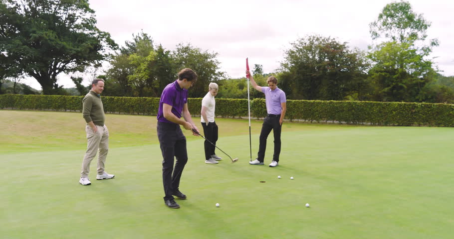 Male golf players wearing uniforms, playing and knocking ball into cup on a course. sport, lifestyle, golf and activity.