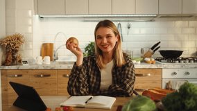 Portrait of a beautiful girl eating, biting apple, watching at the camera and smile, sitting at table in kitchen of her house apartment, studying, student, display, healthy, nutrition, vitamins - Powered by Shutterstock - Get 15% off with code: PIKWIZARD15