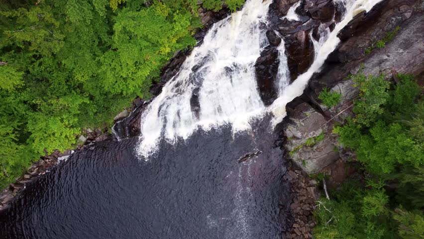 Aerial cinematic view of a cascading waterfall surrounded by lush green trees. Profile Falls New Hampshire.