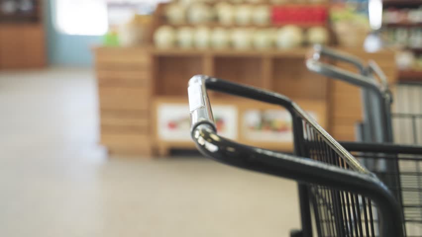 Closeup shopper grabbing cart at grocery store during daytime in Minnesota, USA.