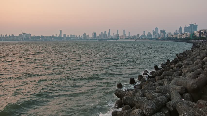 A view from Marine Drive, Mumbai, where people are seen sitting and gazing at the sea. In the background, the city