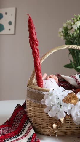 A festive Easter basket with a bright red candle placed in the center, surrounded by fresh spring flowers in soft focus.