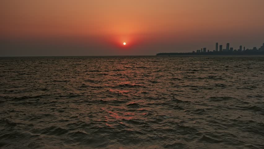 A view from Marine Drive, Mumbai, where people are seen sitting and gazing at the sea. In the background, the city