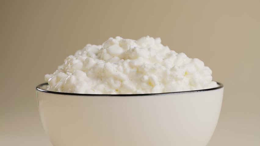 Granulated cottage cheese in bowl with cream on the table. Dairy concept. High quality 4k footage