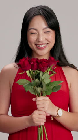 Asian, happy woman and red dress with bouquet of roses in studio for valentines day, romance or love on a white background. Portrait, female person or model with smile or flowers for anniversary date