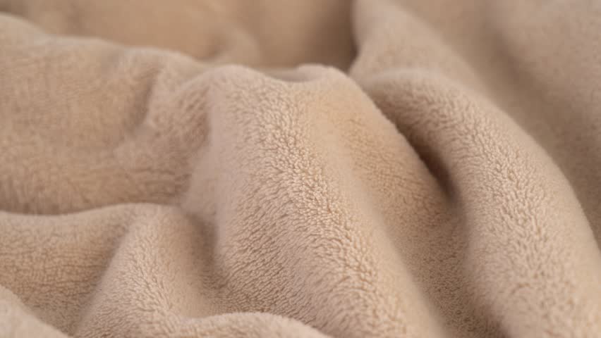 Beige soft plush fabric rotate in circle. Textile material. Texture fabric close up. Fabric sewing toys. Plaid. Fabric background