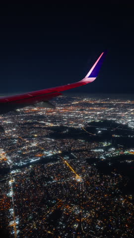 Vertical Screen: Capturing a breathtaking view from an airplane window while flying, showcasing the expansive night sky filled with fluffy clouds, as the plane approaches its landing at the airport