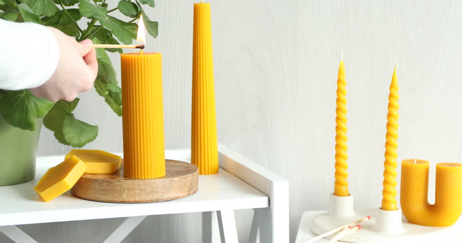 Woman lighting beeswax candle at home, closeup