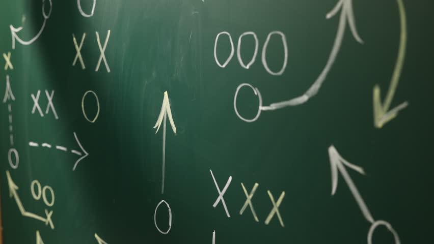 Man drawing American football game scheme on chalkboard, closeup