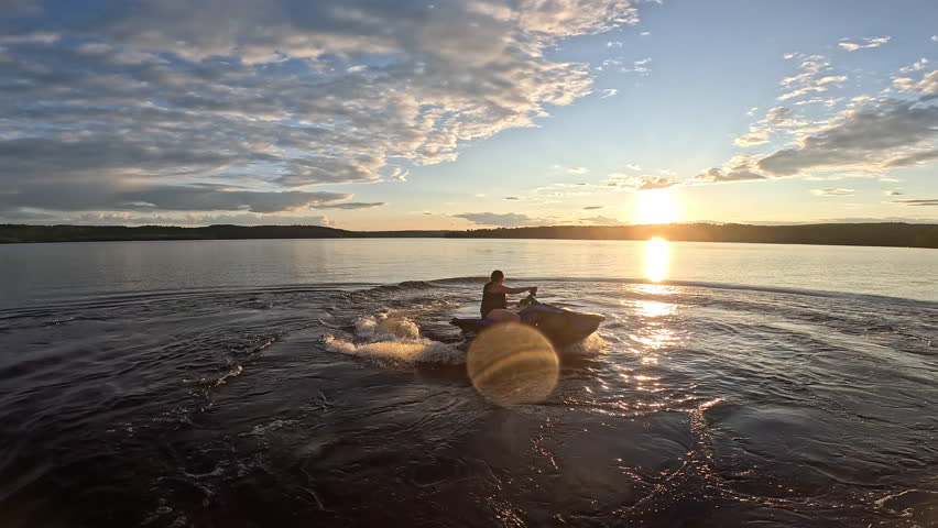 Female rider on personal watercraft going into the sunset