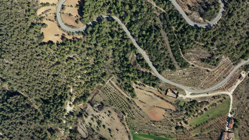 Incredible aerial view of a winding country road between pine-covered mountains in Catalonia, Spain.