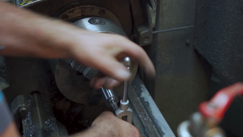 Skilled worker cutting threads on a metal component using a lathe. The video highlights traditional techniques, precise control, and the craftsmanship involved in manual machining operations