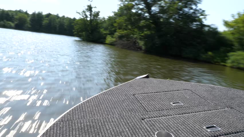 Motorboat gliding smoothly across tranquil river, weaving through verdant riverside vegetation under bright summer sky