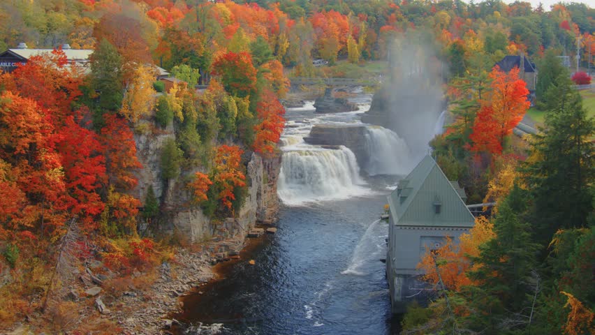 Stunning waterfall at Ausable Chasm in the Adirondacks, with autumn foliage framing the scene, showcasing the natural beauty of the region during peak fall season.