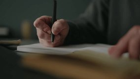 Student hands writing notes with pen in notebook while studying from textbook at home, focused on learning and education, sitting at desk in library with dark interior, close-up, slow motion. - Powered by Shutterstock - Get 15% off with code: PIKWIZARD15