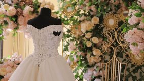 A beautiful wedding dress with a long, lace-trimmed train is displayed on a mannequin. The scene is decorated with flowers and ornate pedestals, creating a romantic atmosphere. - Powered by Shutterstock - Get 15% off with code: PIKWIZARD15