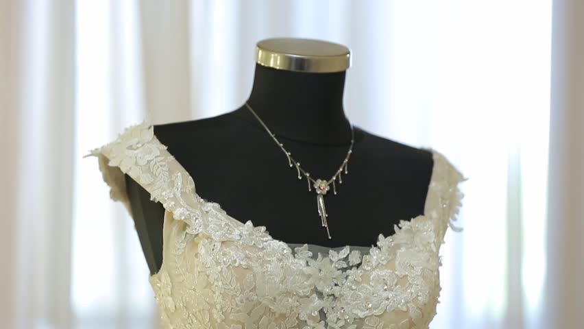 A stunning lace wedding dress is displayed on a mannequin. Surrounded by lights, flowers, sheer curtains, it creates an atmosphere of romance and refined elegance, perfect for bridal fashion