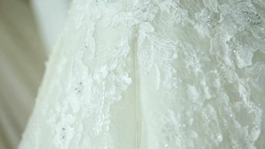 A stunning lace wedding dress is displayed on a mannequin. Surrounded by lights, flowers, sheer curtains, it creates an atmosphere of romance and refined elegance, perfect for bridal fashion