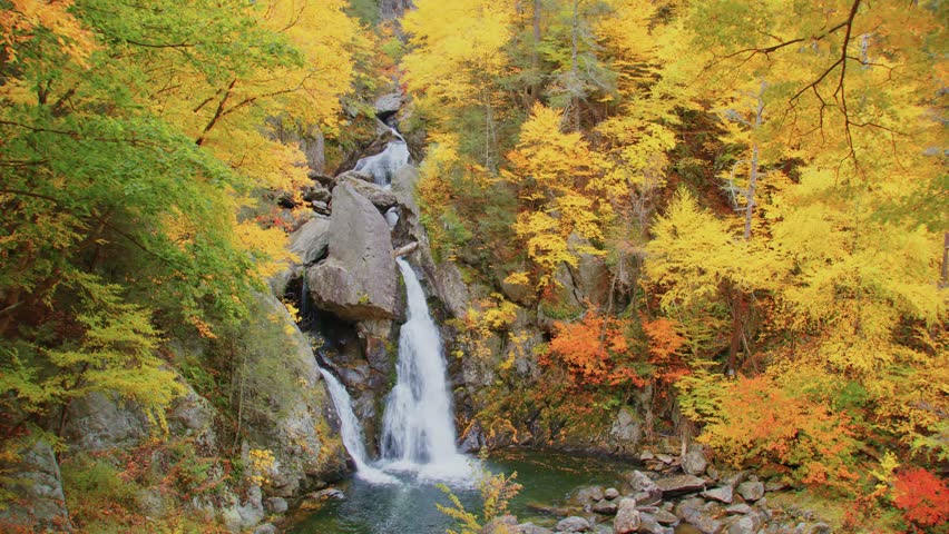 This footage captures the stunning sight of Bash Bish Falls in Bash Bish Falls State Park, the highest waterfall in Massachusetts, surrounded by fall foliage.