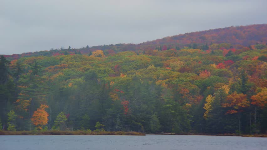 This breathtaking footage captures the beauty of Adirondack Park in New York, featuring a serene lake surrounded by vibrant autumn foliage and forested landscapes.