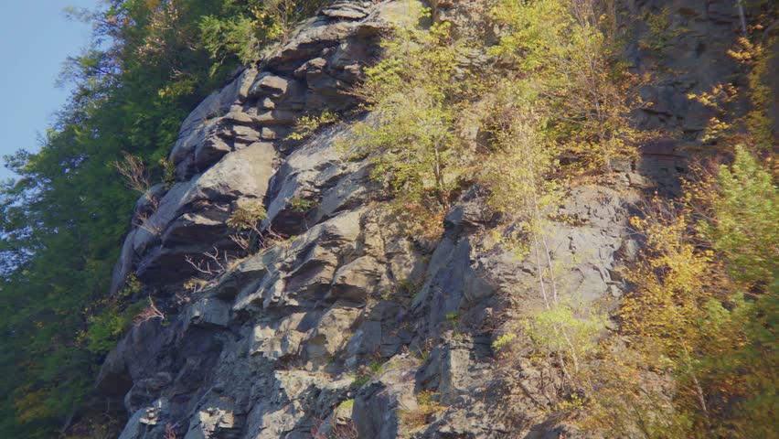 This footage shows a natural rock formation, potentially a cliff or mountainside, surrounded by vegetation near Hawk