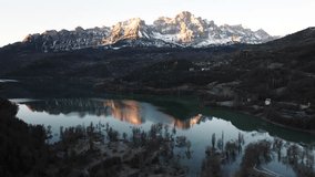 Aerial shot - Warm light from the rising sun illuminates the snowy peaks of Pena Montanesa, casting a golden glow on the tranquil turquoise waters of Ibon de los Banos in the Spanish Pyrenees - Powered by Shutterstock - Get 15% off with code: PIKWIZARD15