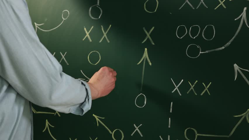 Man drawing American football game scheme on chalkboard, closeup
