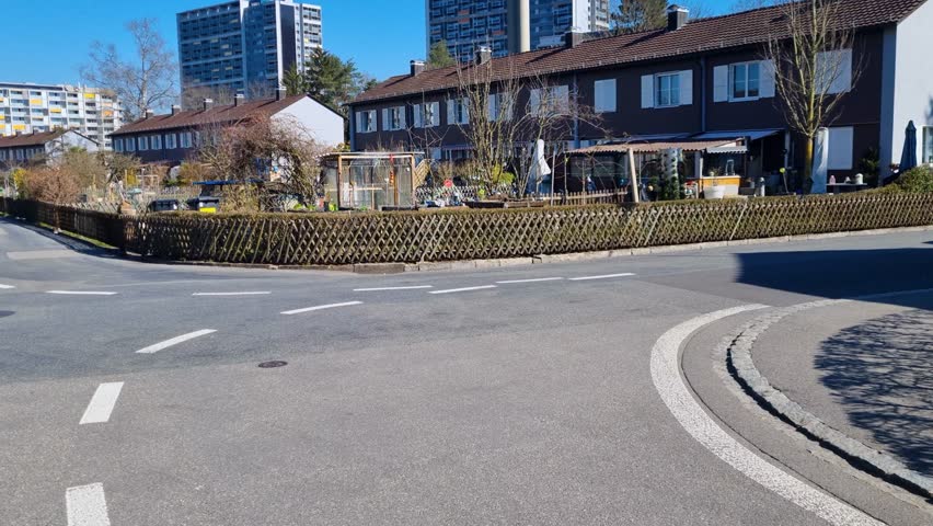 Shot of a residential area in the Bethlehem district of Bern, Switzerland, featuring small family houses with gardens and tall apartment blocks in the background, all set against a clear blue skyy