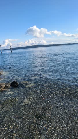 Beach waves in Port Townsend Washington at ground level. Beautiful pebble beach on sunny day.