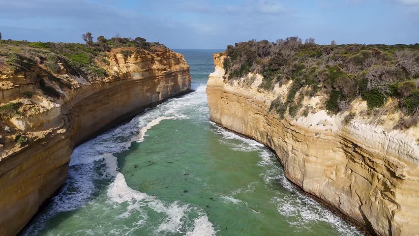 Aerial footage captures the stunning cliffs and turquoise waters of Loch Ard Gorge in Port Campbell, Australia, under bright daylight