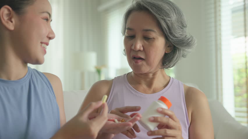 Young adult child give advice to middle age old mum. Love health care older aged mom asia elder people at home happy family help protect aging asian life. Vitamin d c e k zinc omega 3 fish oil pill.