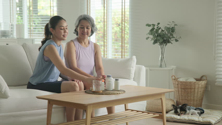 Young adult child give advice to middle age old mum. Love health care older aged mom asia elder people at home happy family help protect aging asian life. Vitamin d c e k zinc omega 3 fish oil pill.