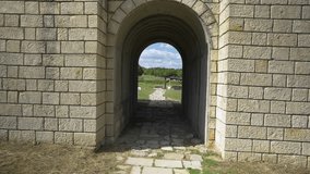 Stone archway tunnel opening into ancient ruins at Veliki Preslav, Bulgaria. The historic passageway is surrounded by lush green fields and remnants of old stone pathways. - Powered by Shutterstock - Get 15% off with code: PIKWIZARD15