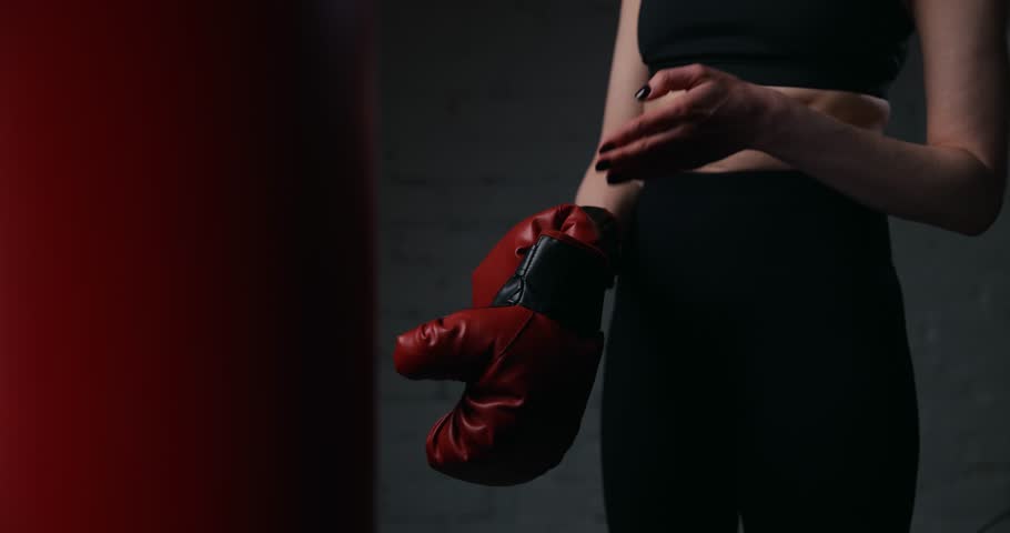 woman putting on boxing gloves before training in a gym