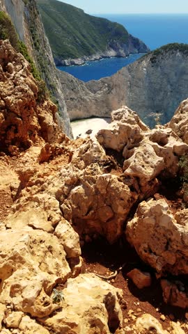 Epic view of beautiful Navagio Beach bay (wreck ship) on Zakynthos Island in Greece. Vertical shot from the edge of the cliff. Dangerously close shot from above the ground. Beautiful sunny day
