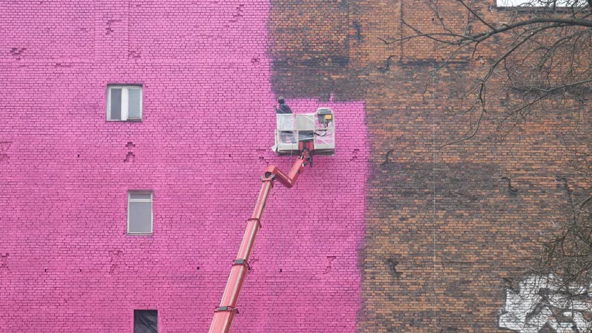 Urban Building  Transformation: Worker Painting a Brick Wall Bright Pink