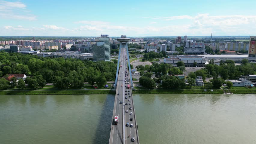 Top down aerial of SNP bridge over the Danube River with cityscape and green zones in Bratislava