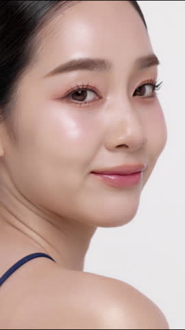 Vertical footage beautiful young Asian woman with healthy facial skin isolated over white background for skincare commercial product advertising. Slow motion shot.