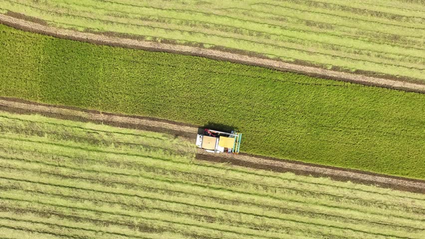 The drone provides a precise aerial view of farm machinery at work, demonstrating the role of technology in enhancing crop harvesting and land use.
