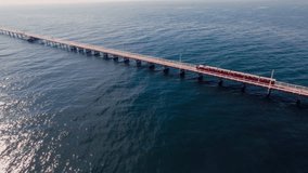 A long wooden pier extends into the sparkling ocean, with a train traveling on its tracks - Powered by Shutterstock - Get 15% off with code: PIKWIZARD15