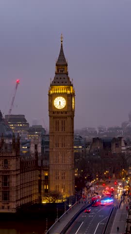 Night to day time lapse view of the Big Ben clocktower and Westminster Bridge in London, England, during a moody winter morning with clouds and fog