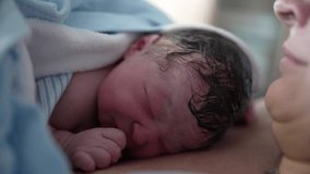 Close-up of newborn baby right after birth resting on mother's chest emphasizing skin to skin contact authentic real life birth moment first minutes of life of infant - Powered by Shutterstock - Get 15% off with code: PIKWIZARD15