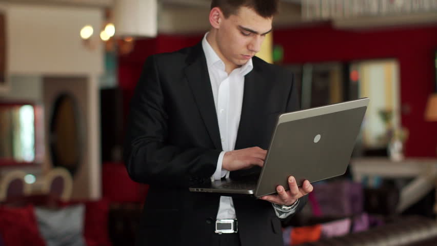 Guy standing in cafe with laptop and typing