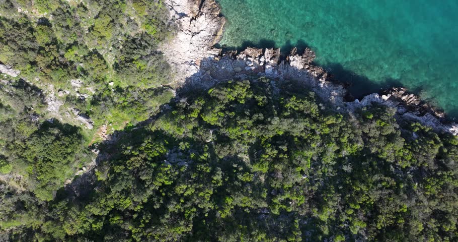 Birdseye aerial of crystal clear blue water and birds flying below along the coastline in Peloponeese, Greece.