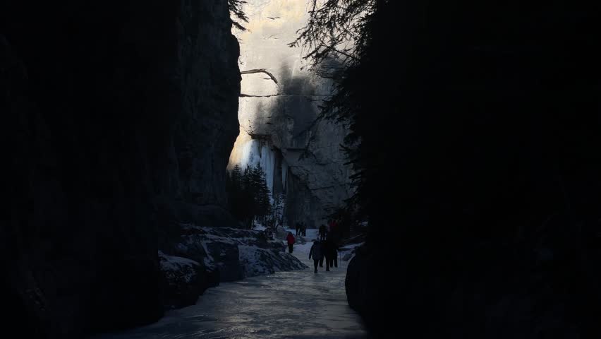 People walking in shadow on frozen creek in canyon