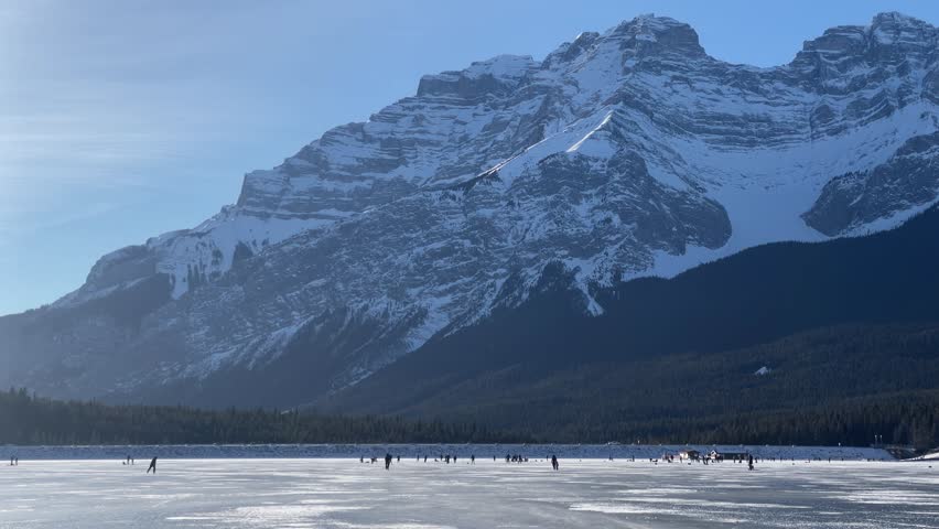 Crowd of people skating on frozen lake Minewanka, Banff, Alberta, Canada