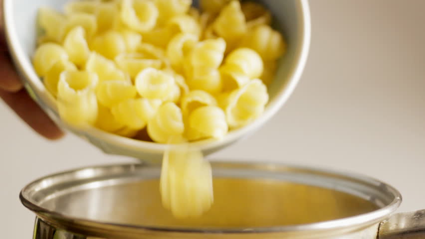 Pouring pasta into saucepan